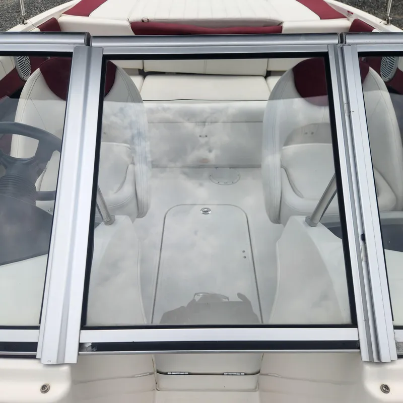 Slide: The Image of 2018 Bayliner 185 Bowrider interior with white and red seating, viewed through windshield. - 22