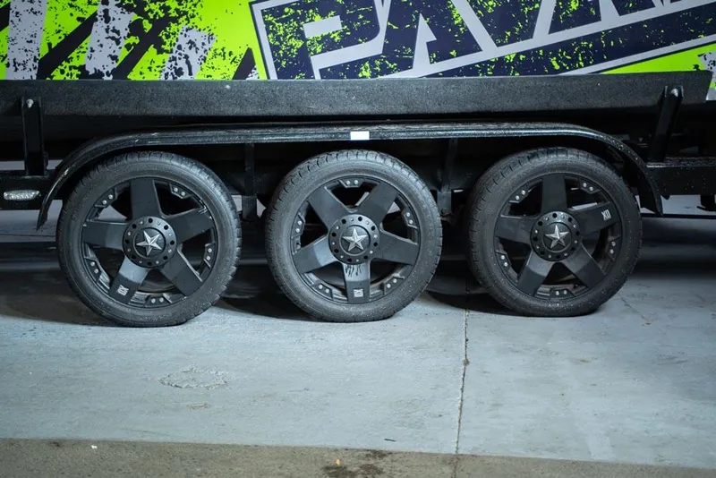 Slide: The Image of 2018 Pavati AL26 boat trailer with triple black wheels and green graphic design. - 8