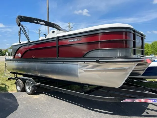 Slide: The Image of 2023 SunCatcher SELECT pontoon boat on trailer, red and silver, side view. - 0