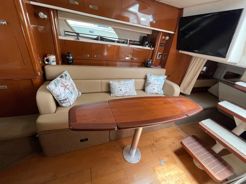 Slide: The Image of Interior of 2012 Sea Ray 350 Sundancer with sofa, wooden table, and TV. - 17