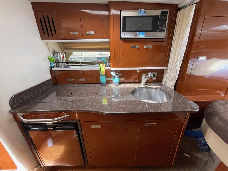 Slide: The Image of 2012 Sea Ray 350 Sundancer kitchen with microwave, sink, and mini-fridge. - 18