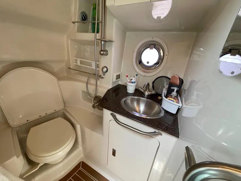 Slide: The Image of 2012 Sea Ray 350 Sundancer bathroom with toilet, sink, and porthole window. - 23