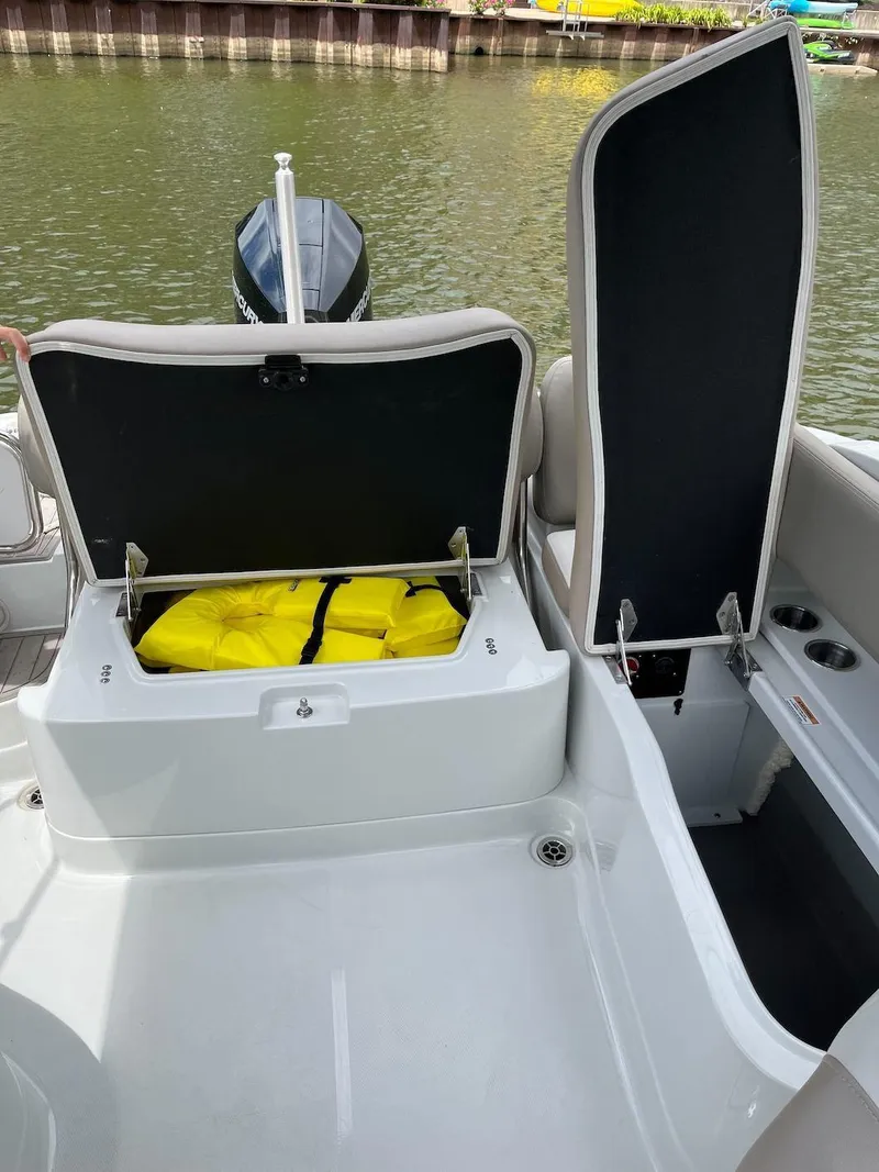 Slide: The Image of 2023 Crownline E 235 XS boat with open storage compartments by the water. - 13