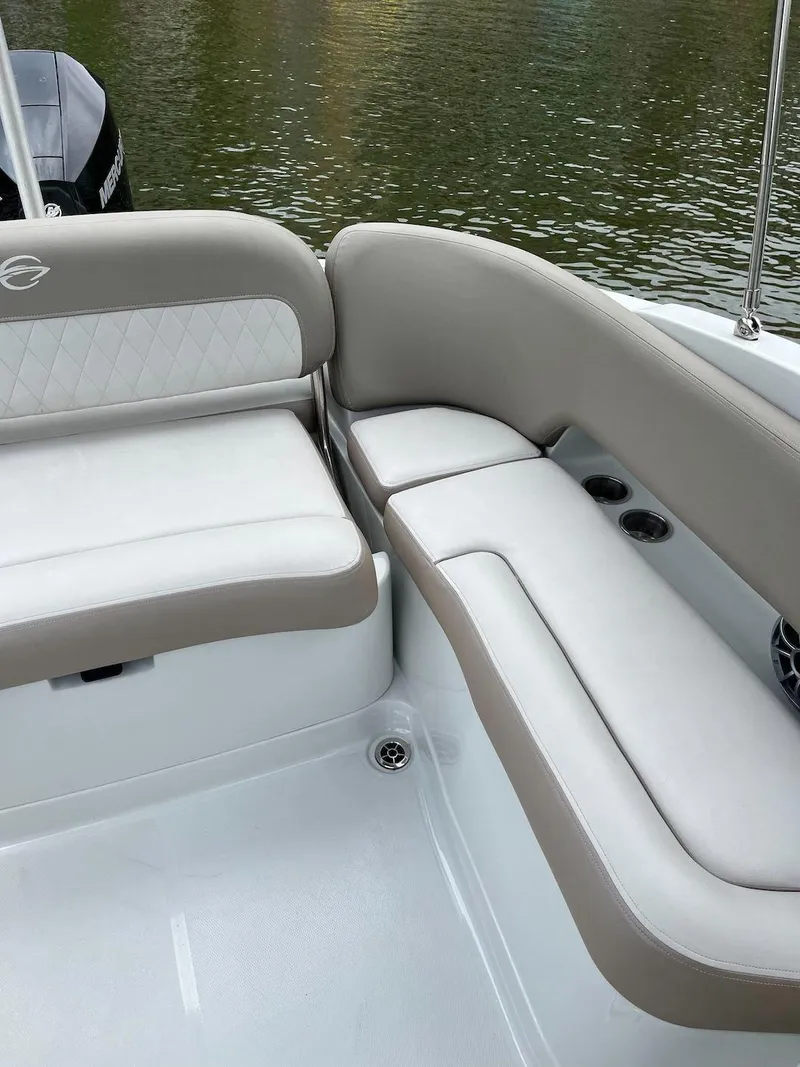 Slide: The Image of 2023 Crownline E 235 XS boat interior with cushioned seating by the water. - 8