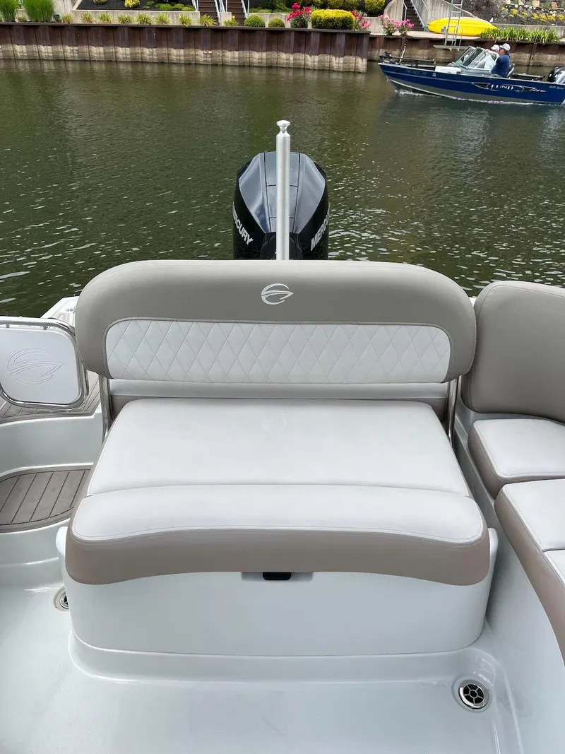Slide: The Image of 2023 Crownline E 235 XS boat interior with cushioned seating by the water. - 9