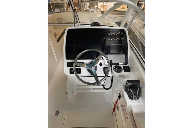 Slide: The Image of 2024 Edgewater 248CX Crossover boat dashboard with steering wheel and control panel. - 11