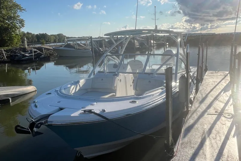 Slide: The Image of 2024 Edgewater 248CX boat docked on a sunny day, surrounded by calm water. - 2