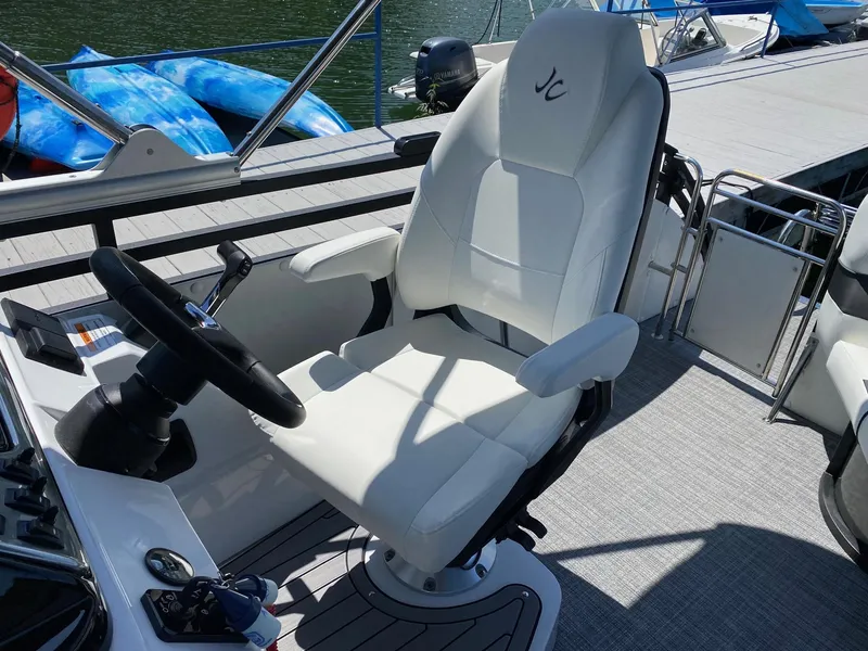 Slide: The Image of Captain's chair on the 2024 JC NEPTOON SPORT 21TT boat, docked by the water. - 13