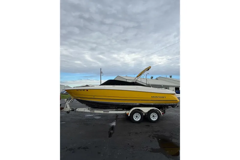 Slide: The Image of 2007 Monterey 214FS boat in yellow on a trailer, parked outdoors under cloudy skies. - 16