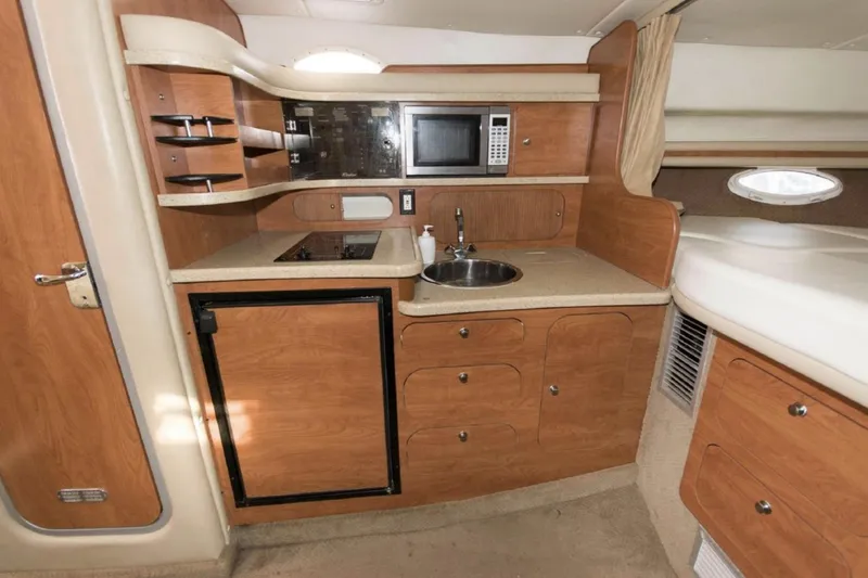 Slide: The Image of 2006 Rinker 342 Express Cruiser kitchen with microwave, sink, and wooden cabinetry. - 10