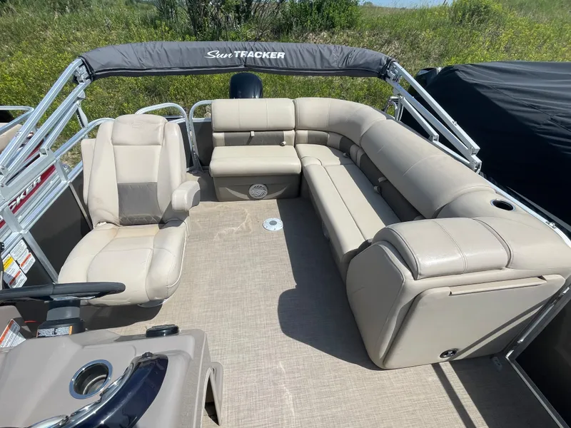 Slide: The Image of 2021 Sun Tracker Party Barge 20 DLX interior with beige seating and steering console. - 7