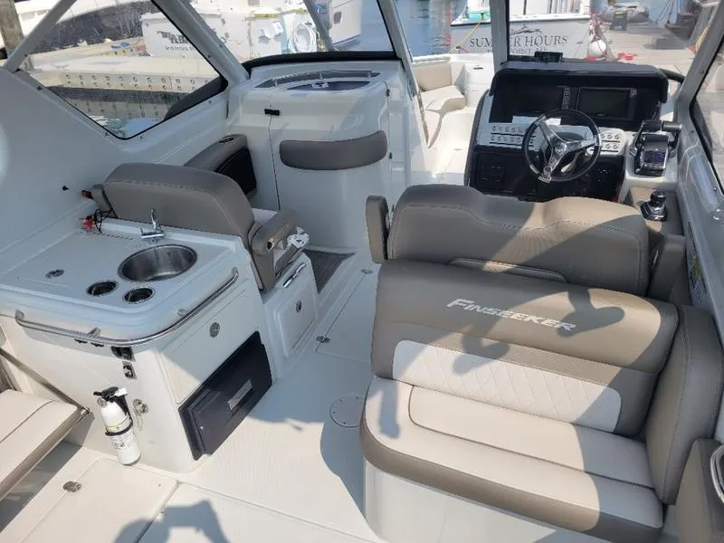Slide: The Image of 2024 Finseeker 260 DC boat interior with seating, steering, and kitchenette. - 18
