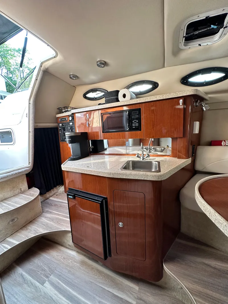 Slide: The Image of 2006 Regal Commodore boat interior with kitchenette, featuring wood cabinetry, sink, and appliances. - 12