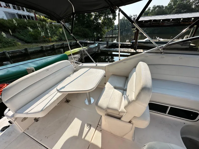 Slide: The Image of 2006 Regal Commodore boat interior with seating and table, docked near lush greenery. - 3