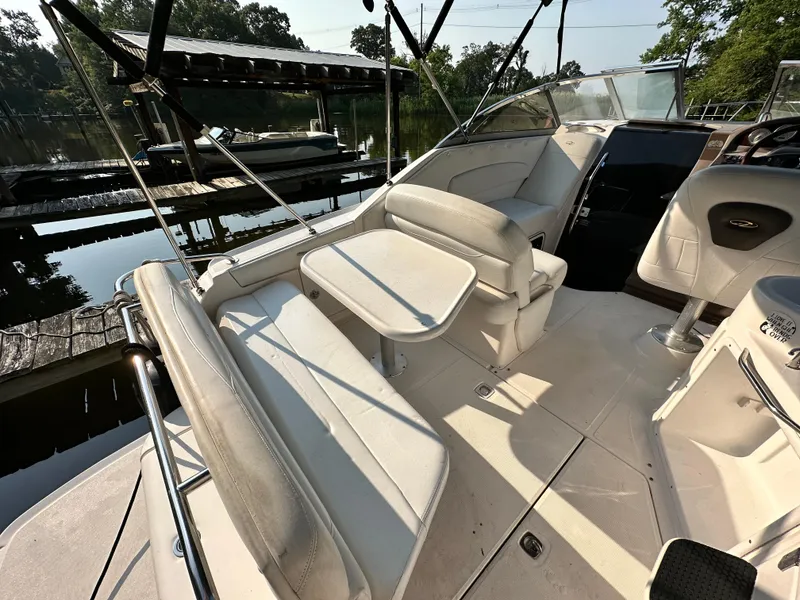 Slide: The Image of 2006 Regal Commodore boat interior with white seating and table, docked by a serene lake. - 8