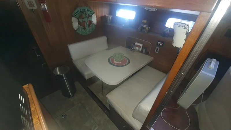Slide: The Image of 1965 Chris-Craft 56 Roamer interior dining area with white seating and wooden walls. - 10