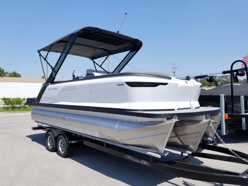 Slide: The Image of 2025 Manitou Cruise pontoon boat on a trailer under clear blue sky. - 3