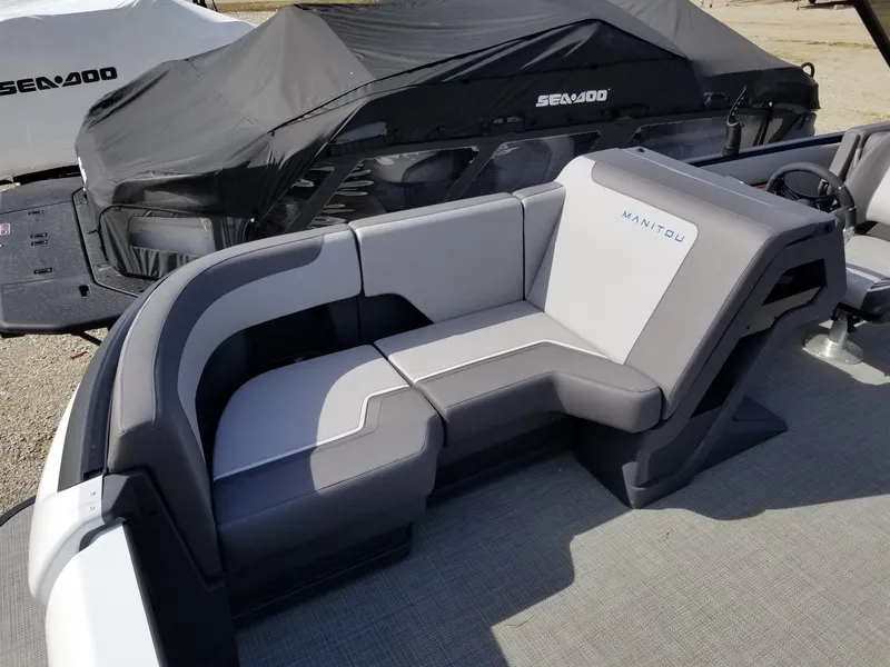 Slide: The Image of 2025 Manitou Cruise boat with gray seating and covered Sea-Doo in the background. - 33