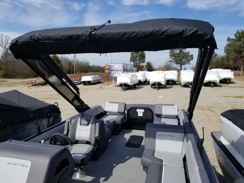 Slide: The Image of 2025 Manitou Cruise pontoon boat with canopy in a dealership lot. - 35