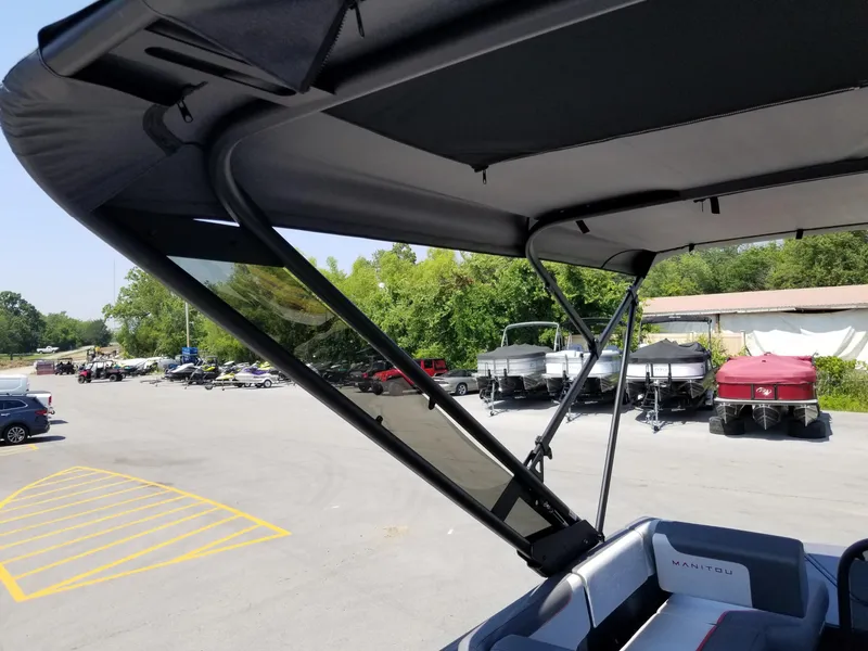 Slide: The Image of 2025 Manitou Cruise boat with canopy, parked in a lot with other boats. - 5