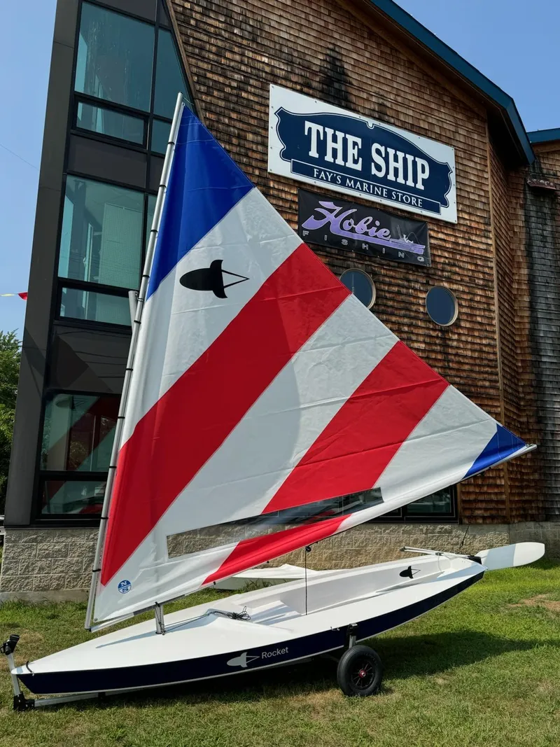 Slide: The Image of 2025 Dinghy Rocket Board Boat with colorful sail outside marine store. - 2