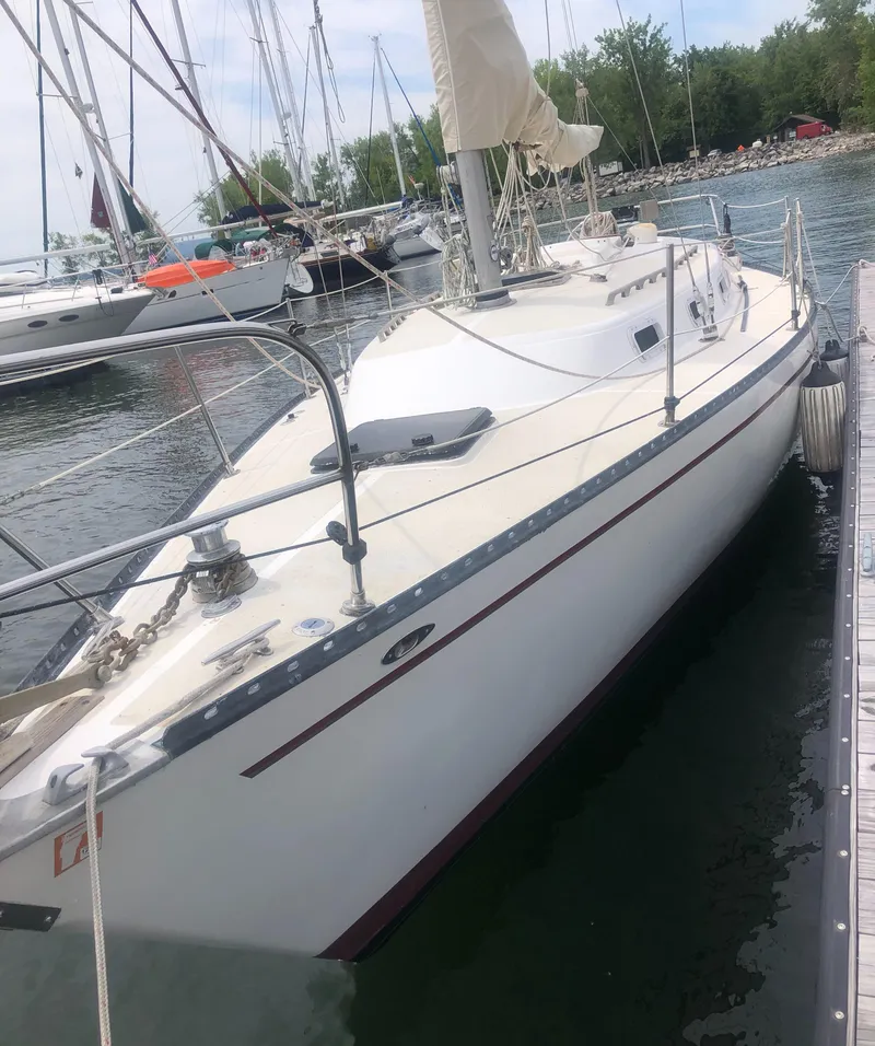 Slide: The Image of 1980 Tartan 33 sailboat docked in a marina, surrounded by water and other boats. - 1