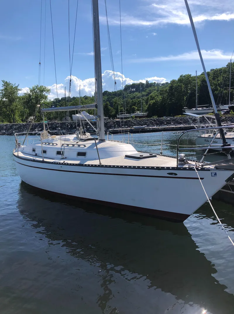 Slide: The Image of 1980 Tartan 33 sailboat docked in a serene marina setting. - 2
