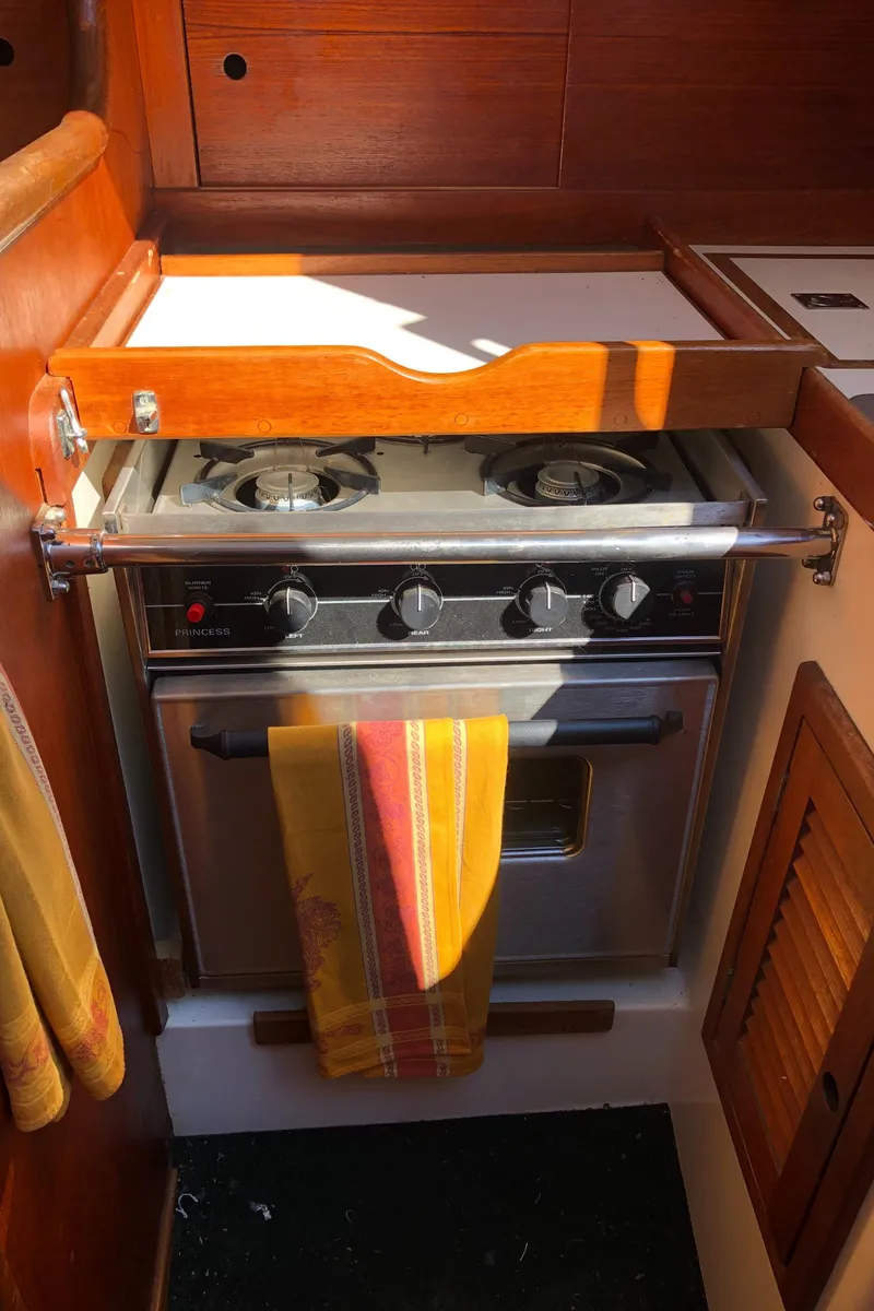 Slide: The Image of Vintage 1980 Tartan 33 yacht kitchen with stove and wooden cabinetry. - 34