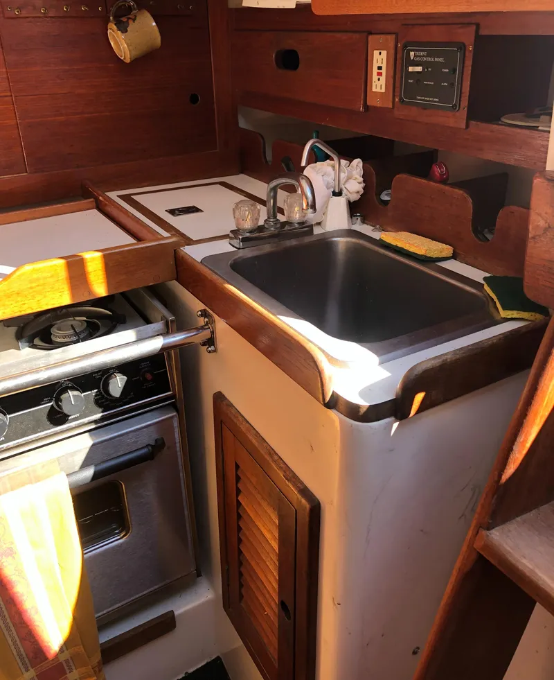Slide: The Image of 1980 Tartan 33 yacht kitchen with sink, stove, and wooden cabinetry. - 35
