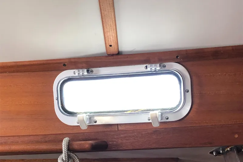 Slide: The Image of Porthole window on 1980 Tartan 33 sailboat interior with wooden trim. - 39