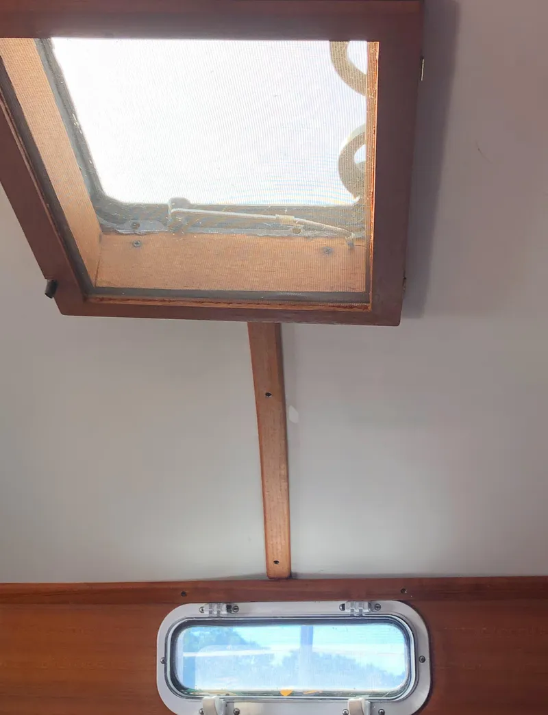 Slide: The Image of Interior view of a 1980 Tartan 33 sailboat, featuring a wooden hatch and porthole. - 41