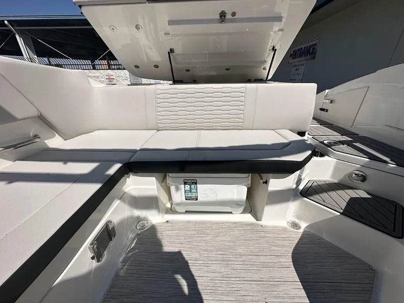 Slide: The Image of 2024 Sea Ray SPX 230 boat interior with white cushioned seating and storage compartment. - 20