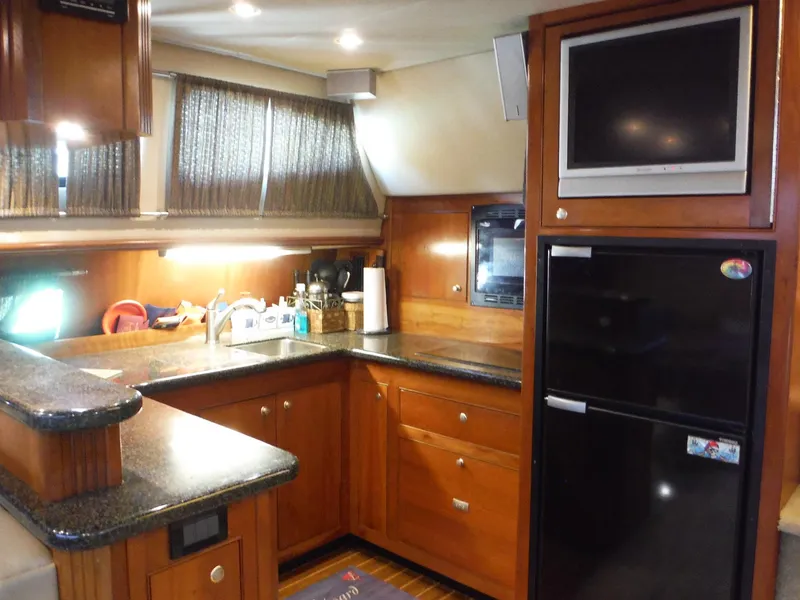 Slide: The Image of 2005 Cruisers Yachts 455 Express Motoryacht kitchen with wood cabinetry and modern appliances. - 19