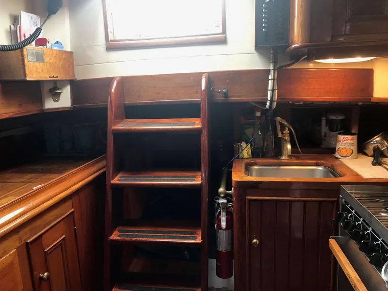 Slide: The Image of 1983 Custom Murray Peterson Coaster III yacht interior with wooden cabinetry, sink, and ladder. - 3