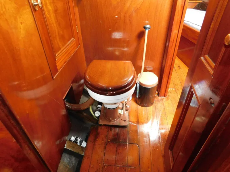 Slide: The Image of 1983 Custom Murray Peterson Coaster III boat interior with wooden toilet and polished wood finish. - 8
