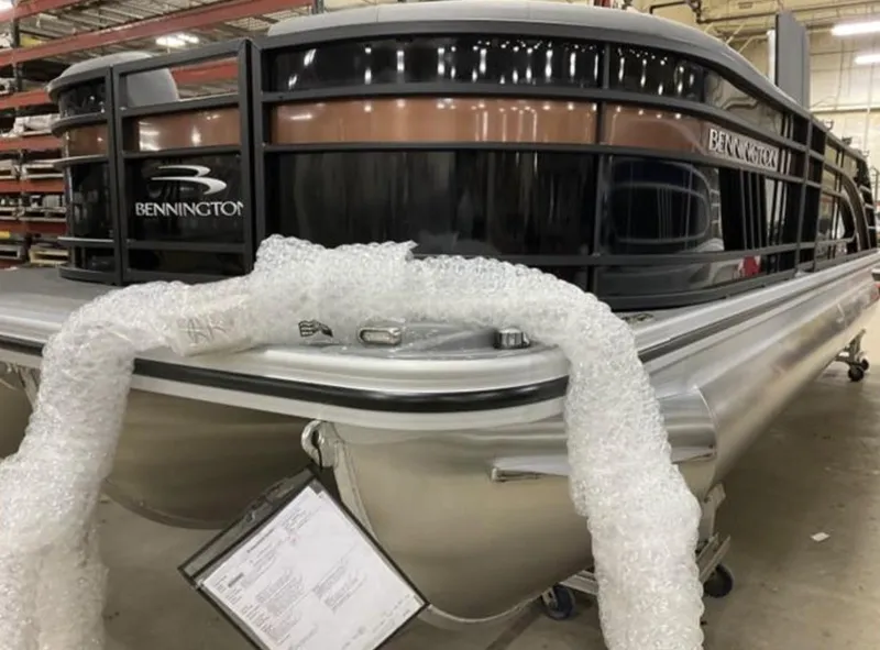 Slide: The Image of 2022 Bennington 23 LSB Swingback pontoon boat in a showroom, partially wrapped in bubble wrap. - 10