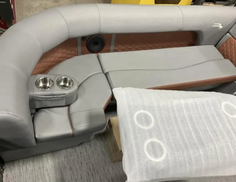 Slide: The Image of 2022 Bennington 23 LSB Swingback boat interior with gray and tan seating, cup holders, and speaker. - 8
