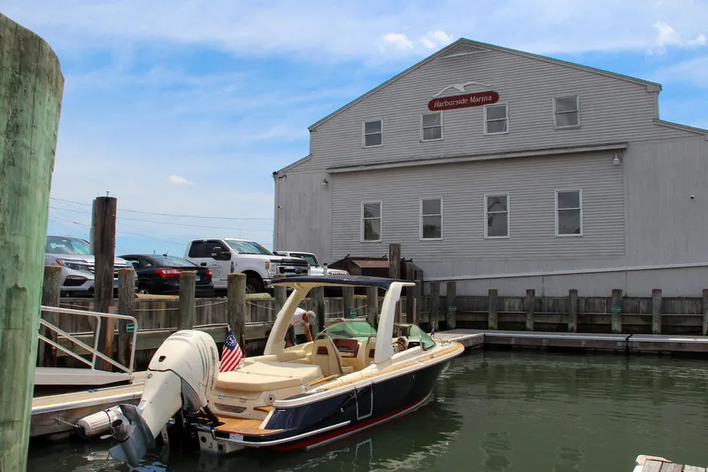 Slide: The Image of 2022 Chris-Craft Launch 25 GT docked at a marina with a building in the background. - 0