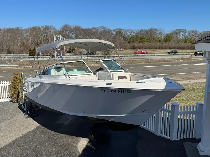 The Image of 2024 Sailfish 226 boat with canopy, parked near a road and white fence. - 0