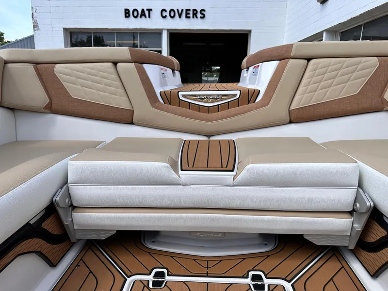 Slide: The Image of 2023 Nautique G21 boat interior with tan and white upholstery, wood flooring, and diamond stitching. - 14