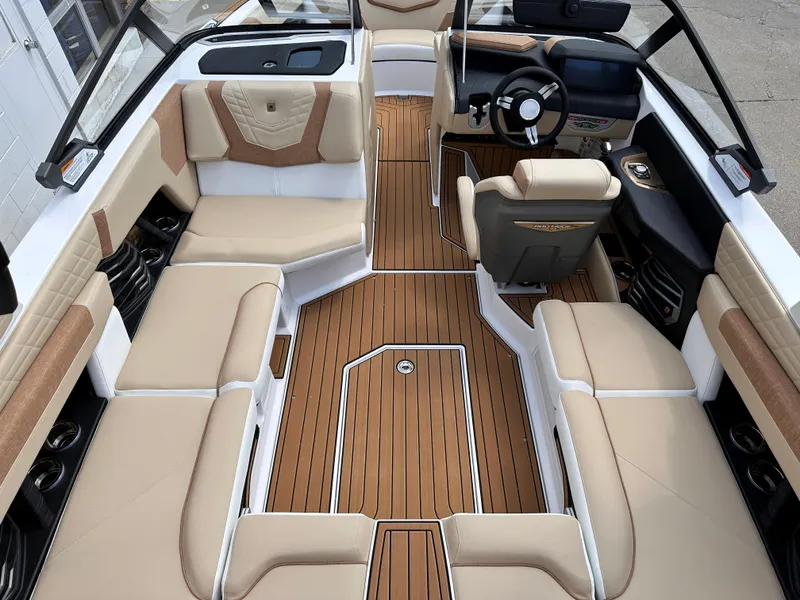 Slide: The Image of 2023 Nautique G21 boat interior with tan and white seating, teak flooring, and modern dashboard. - 18