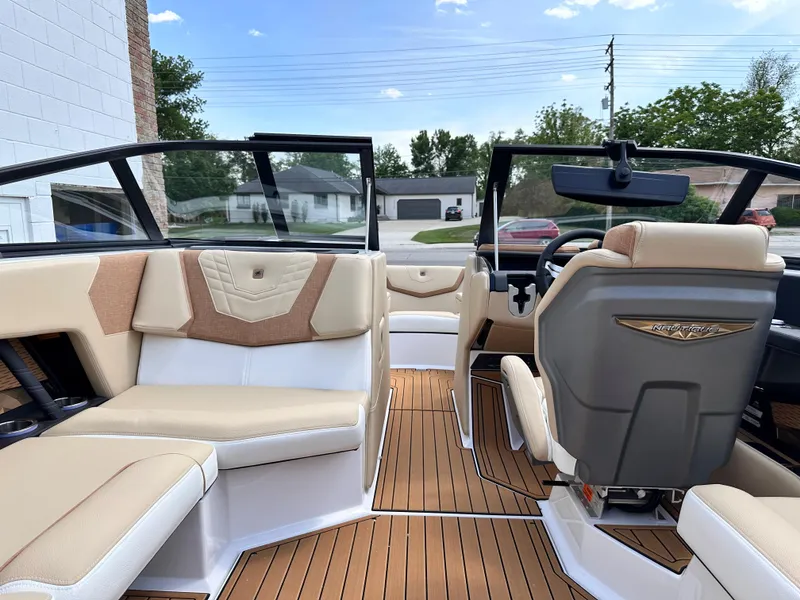 Slide: The Image of 2023 Nautique G21 boat interior with beige and white seating, wooden flooring, and modern dashboard. - 8