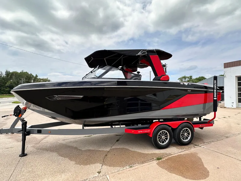 The Image of 2023 Nautique G23 boat on a trailer, black and red design. - 0