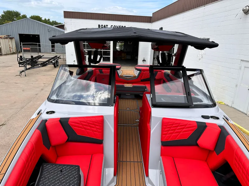 Slide: The Image of 2023 Nautique G23 boat with red and black interior, docked near a boat cover shop. - 10