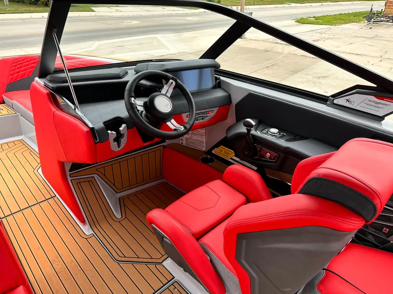 Slide: The Image of 2023 Nautique G23 boat interior with red and black seats, modern dashboard, and wooden flooring. - 12