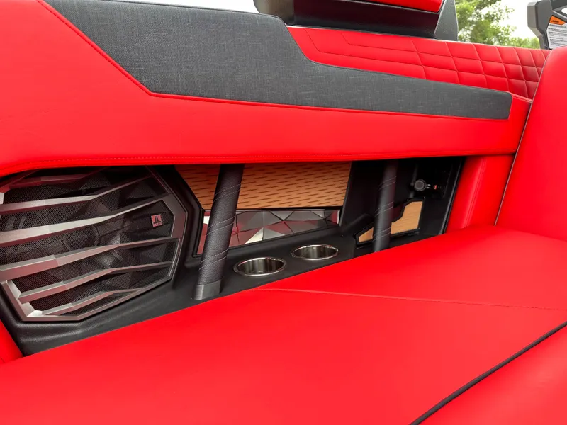 Slide: The Image of 2023 Nautique G23 interior, red upholstery with speaker and cup holders. - 26