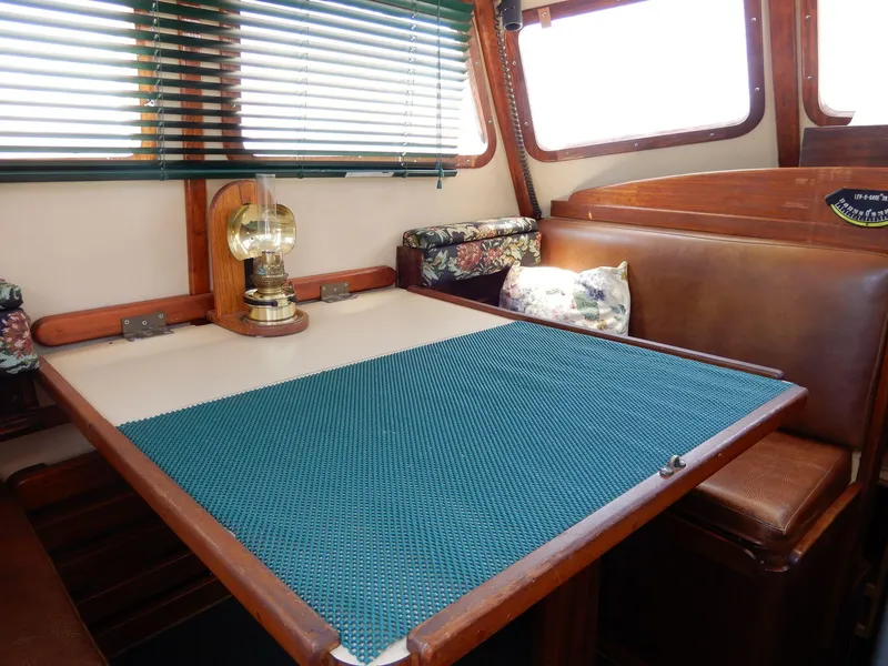 Slide: The Image of 1977 Ted Brewer Jason Pilothouse Offshore interior with dining area, wooden table, and vintage lamp. - 5