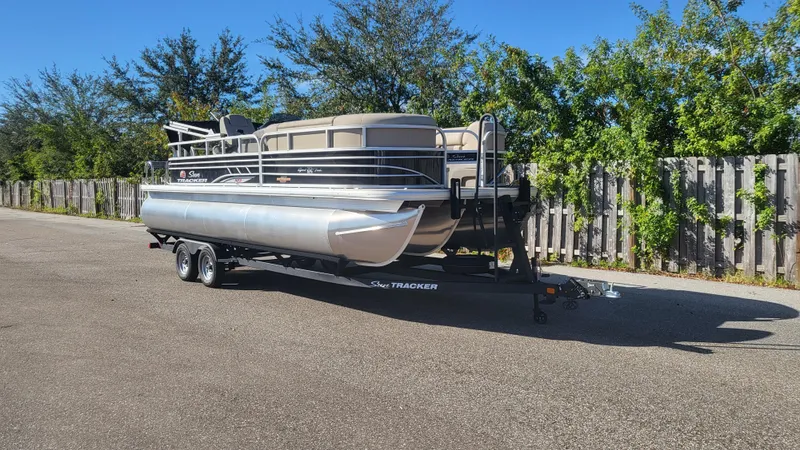 The Image of 2023 Sun Tracker SportFish 22 XP3 pontoon boat on trailer, parked outdoors. - 0