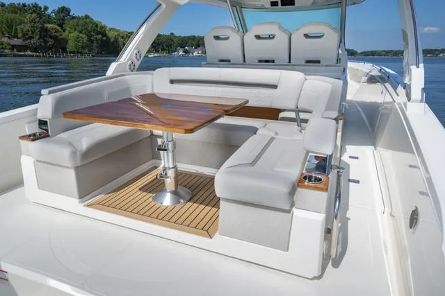 Slide: The Image of 2024 Tiara Yachts 38LS luxury boat with spacious seating and wooden table on deck. - 16