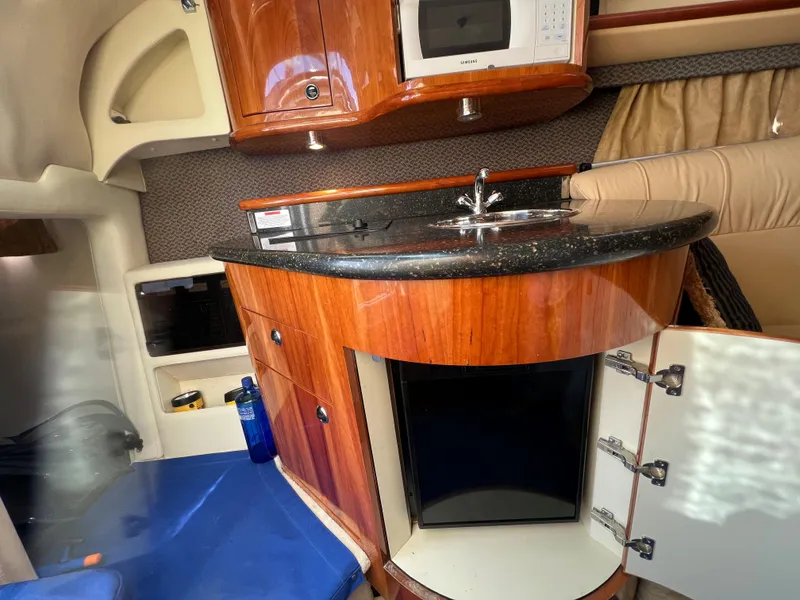 Slide: The Image of 2004 Cobalt 360 boat interior with kitchenette, microwave, sink, and storage cabinets. - 23